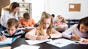 Lernende Kinder, im Hintergrund eine Lehrkraft